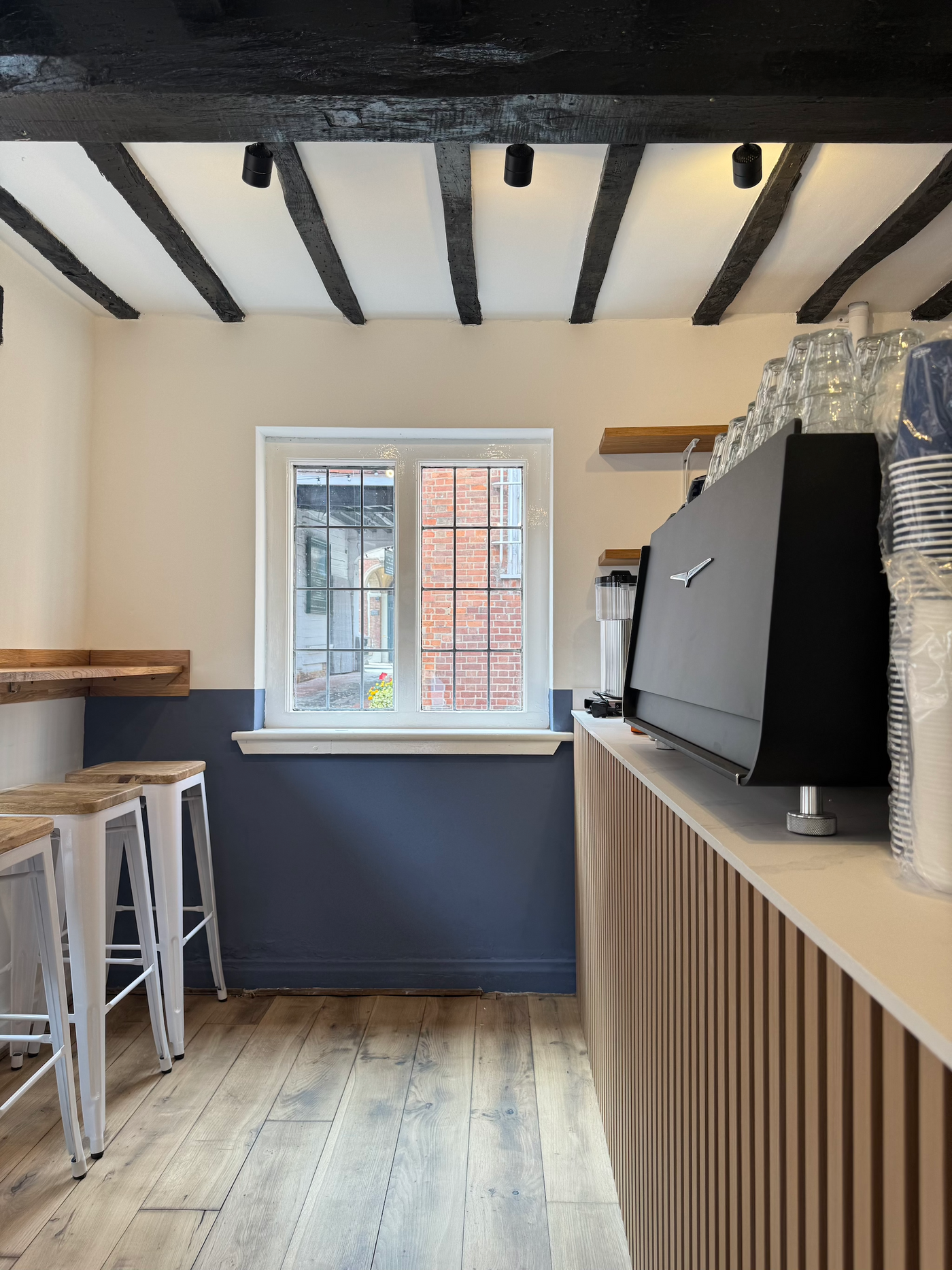 Modern kitchen with wooden counter, stools, and a window.