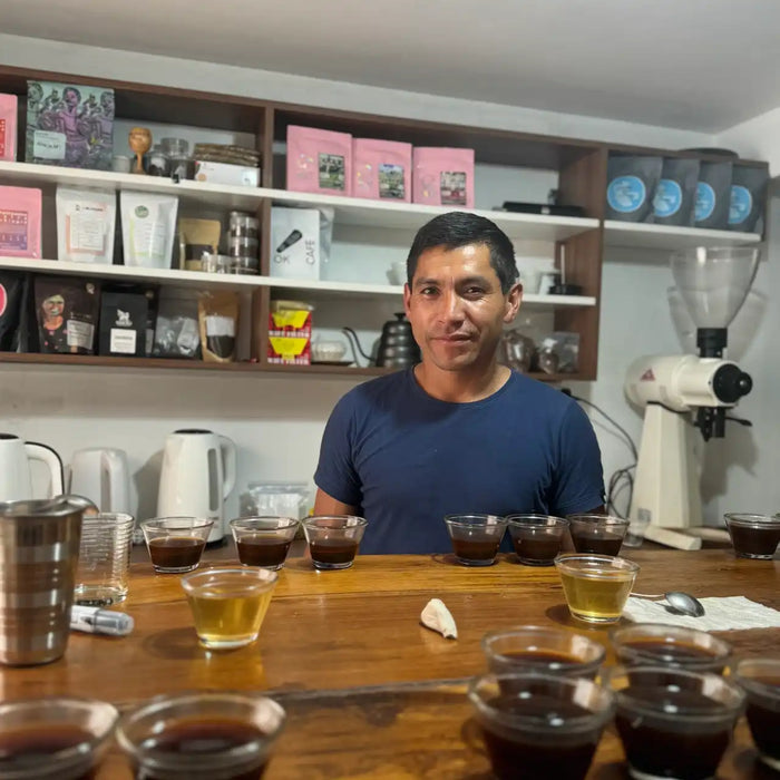 Man standing behind a counter with coffee samples in small cups