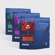 Three blue KOTA coffee bags on a white background