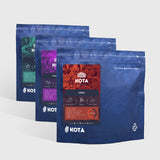 Three blue KOTA coffee bags on a white background