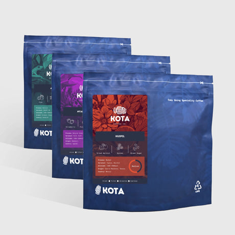 Three blue KOTA coffee bags on a white background